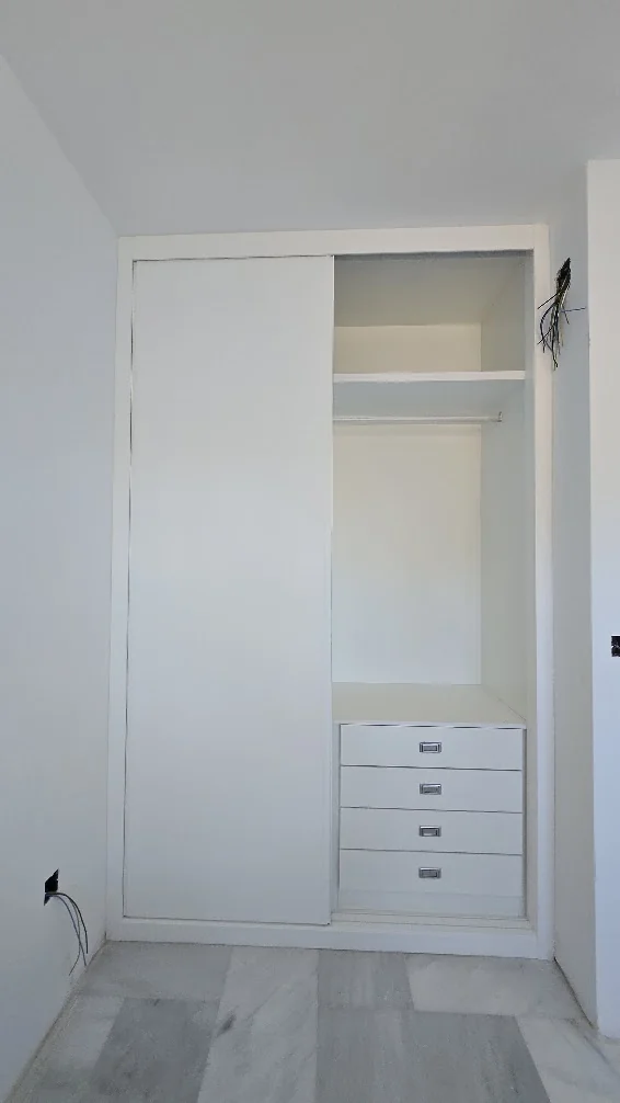 Zona derecha del armario con cajonera cerrada y barra para colgar